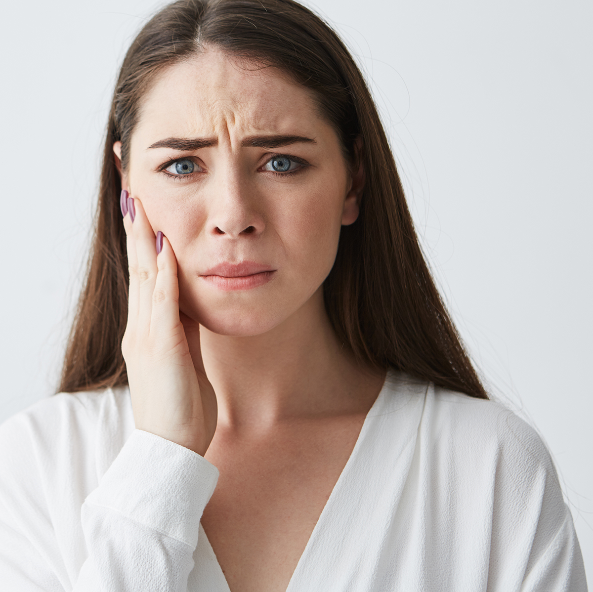 A woman resting her hand against her jaw, with visible jaw discomfort