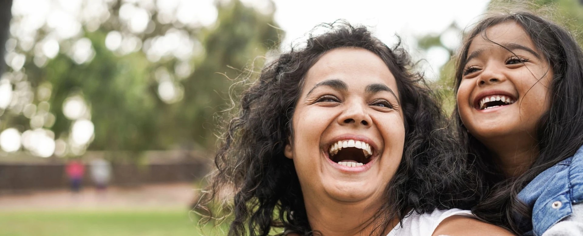 A mother laughing with her daughter outdoors