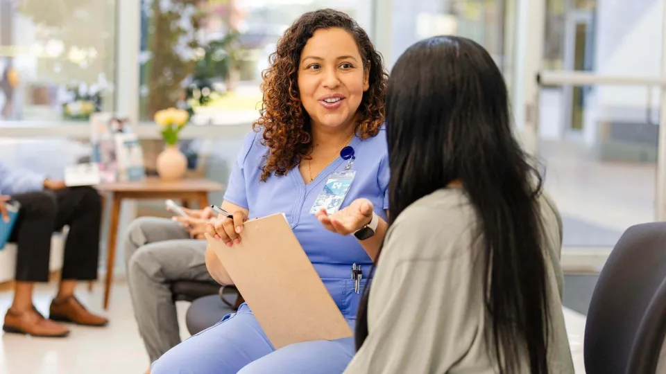 A clinician in scrubs talking with a patient in the office about the PRF process